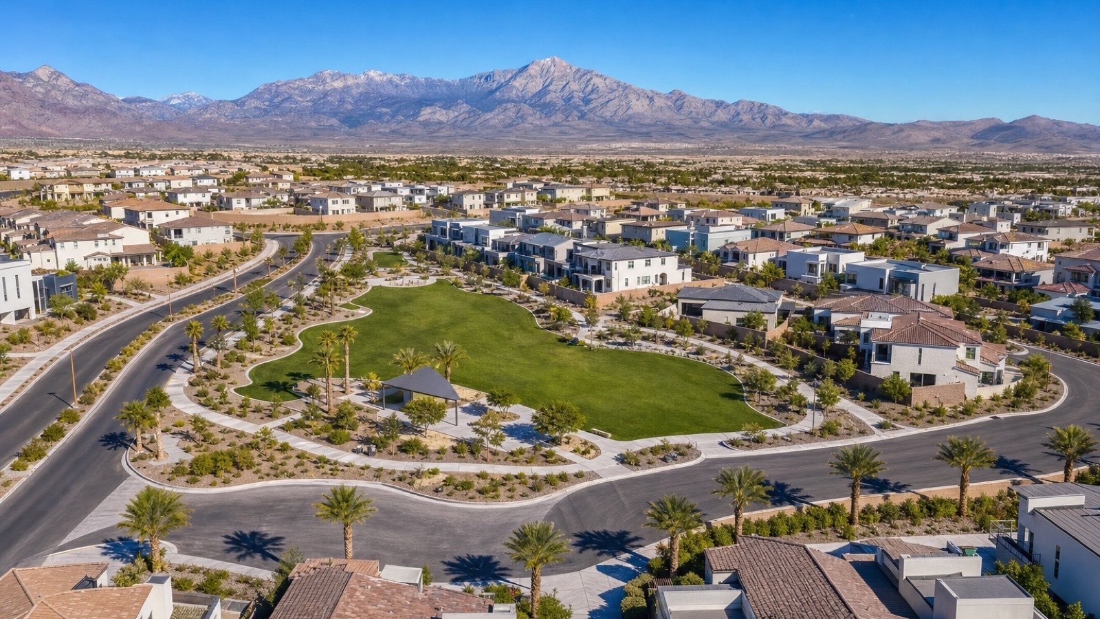 Enterprise neighborhood streetscape in south Las Vegas with newer-construction single-family homes, manicured front yards, and the desert mountain backdrop